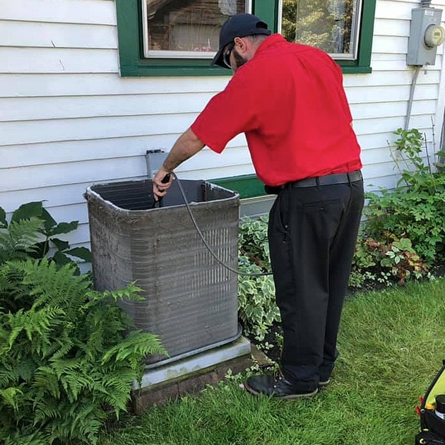 As part of our AC tune-up in Tonawanda, NY, our technician cleans out the inside of the AC condenser unit.