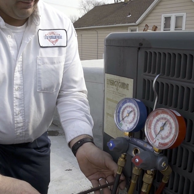 During an AC repair visit, our technician diagnoses the problem by checking the unit's refrigerant levels.