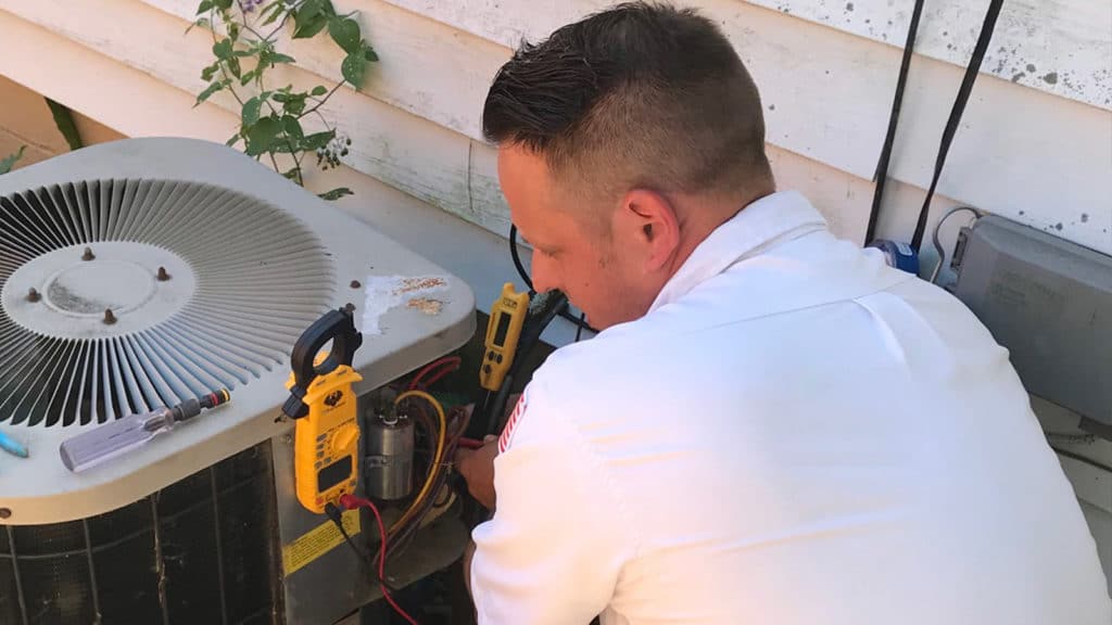 Our technician works on an air conditioner as part of our fast, reliable AC repair service here in Western New York.