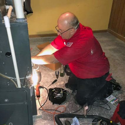 One of our experienced techs uses a work light to see inside of this furnace as part of an inspection and tune-up.