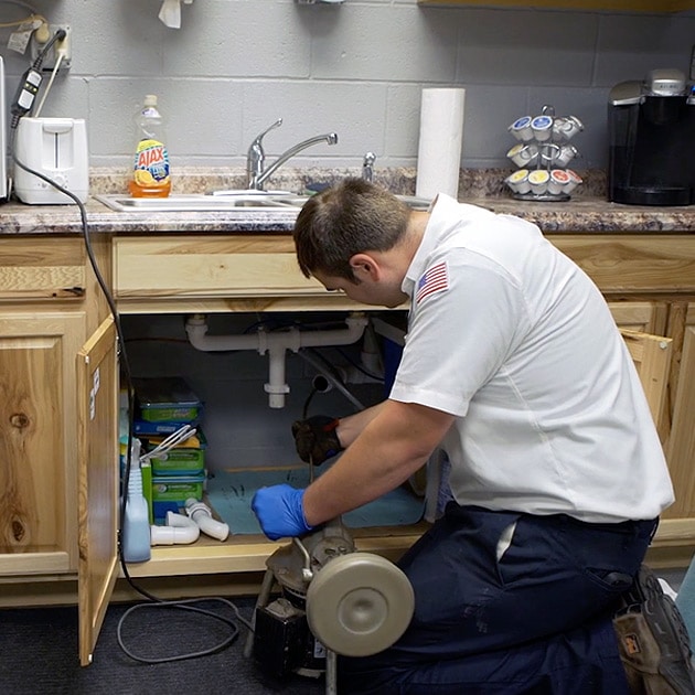 Our plumber uses a specialized snake tool to clear out a tough clog in this business' kitchen sink.